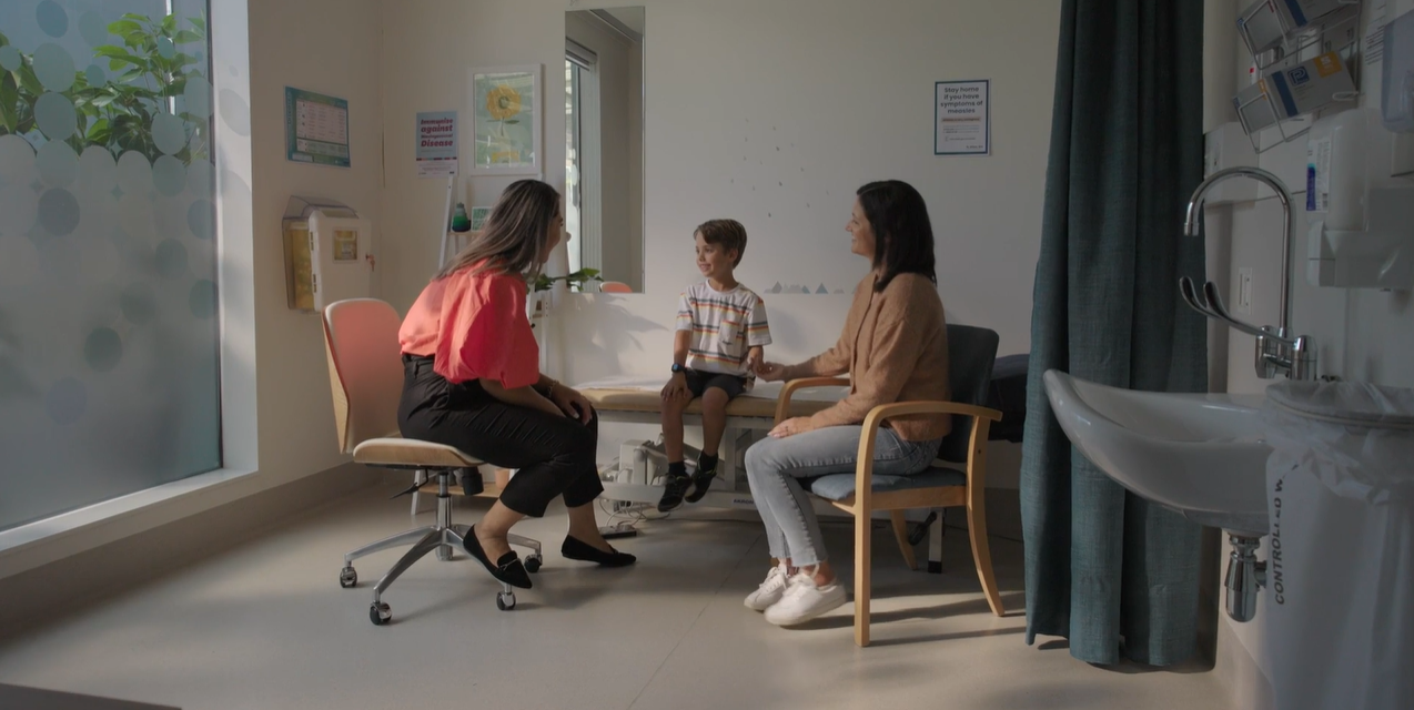 A female General Practitioner sitting with a young male patient and his mother during a consult 